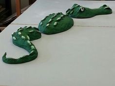 two cakes shaped like alligators sitting on top of a white tablecloth covered counter