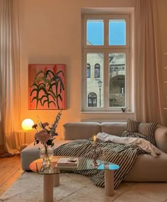 a living room filled with furniture and a large window overlooking a cityscape in the distance