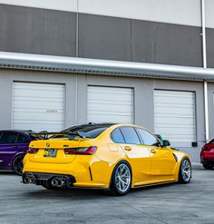 three different colored cars parked in front of garage doors