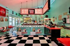 the interior of a diner with checkered flooring and neon signs on the ceiling