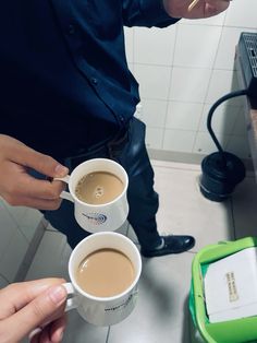 two people holding coffee cups in their hands