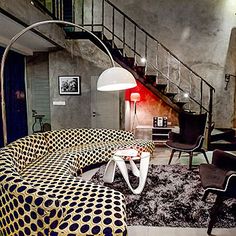 a living room filled with lots of furniture next to a stair case on the wall