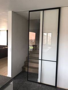 an open door leading to a living room with stairs in the back ground and a couch on the other side