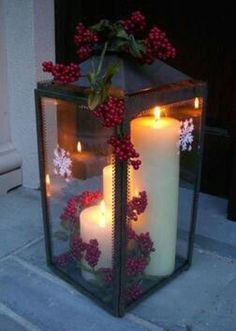 two white candles are sitting in a glass lantern