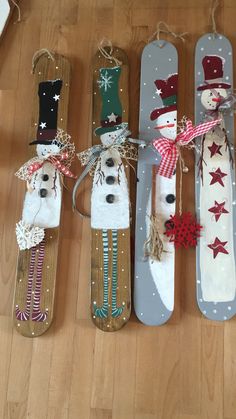 four snowmen made out of sleds sitting on top of a wooden floor