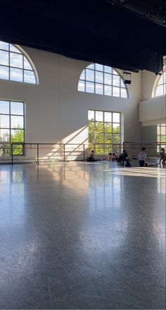 an empty room with large windows and people sitting on benches