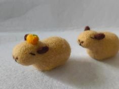 two small stuffed animals sitting next to each other on a white tablecloth covered surface