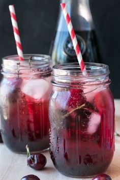 two mason jars filled with liquid and cherries