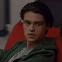 a young man sitting in a red chair looking at the camera