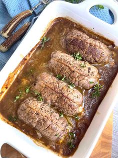 meatloaf with gravy and herbs in a white casserole dish