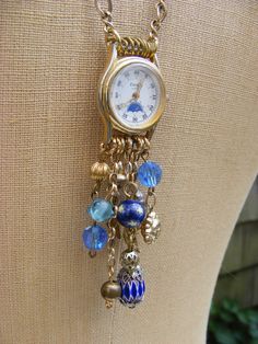 a gold watch with blue beads hanging from it's side on a mannequin