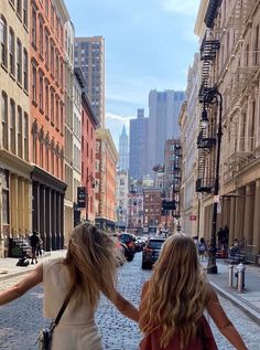 two girls walking down the street with their arms around each other