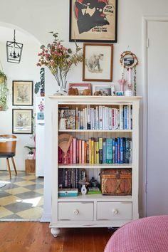 a bookshelf filled with lots of books next to a bed