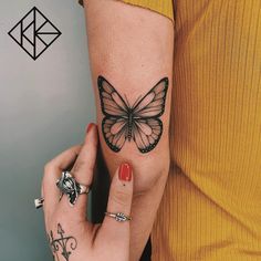 a woman's hand with a butterfly tattoo on her left arm and the other hand