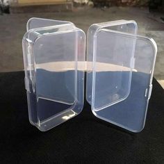 two clear plastic containers sitting next to each other on a black cloth covered table top