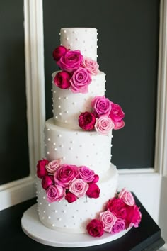 a three tiered white cake with pink flowers on top