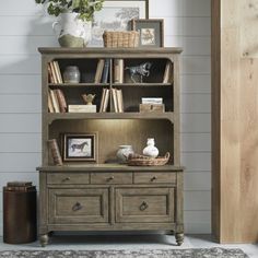 a bookcase with drawers and pictures on it in a room next to a door