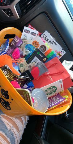 a yellow basket filled with lots of items inside of a car