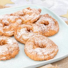 powdered sugar covered donuts on a blue plate