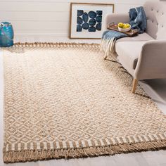 a living room area with a couch, chair and rug on the floor in front of a white wall