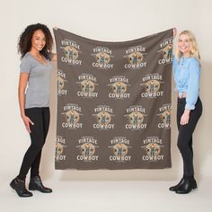 two women standing next to each other holding up a large banner with the words vintage cowboy on it