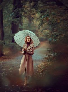 a woman standing in the woods holding an umbrella