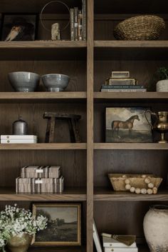 a wooden bookcase filled with lots of books and vases on top of it