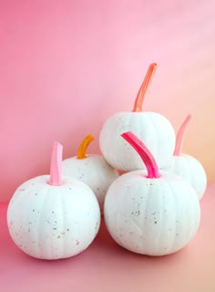 three white pumpkins sitting on top of each other in front of a pink background