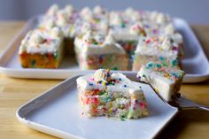 a piece of cake with white frosting and sprinkles is on a plate