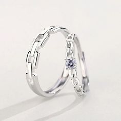 two silver rings with a white diamond on each side and a chain around the middle