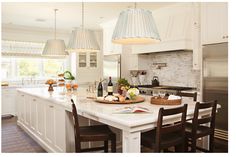 a large kitchen with an island in the middle and two pendant lights hanging from the ceiling