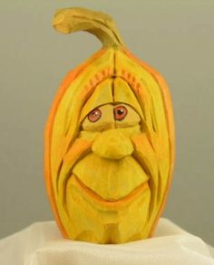 a carved pumpkin with an evil face on it's head, sitting on top of a white cloth