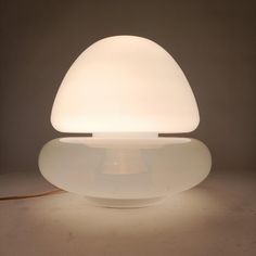 a white lamp sitting on top of a table next to a brown corded light