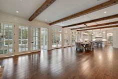 an empty living room with wood floors and french doors leading to the dining room area