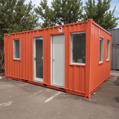 an orange shipping container sitting on top of a parking lot next to trees and buildings