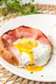 a white plate topped with an egg and ham