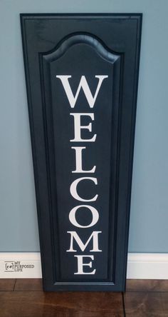 a welcome sign on the floor in front of a blue wall with white lettering that says welcome