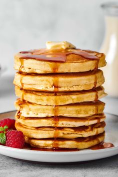 stack of pancakes with syrup and strawberries on plate