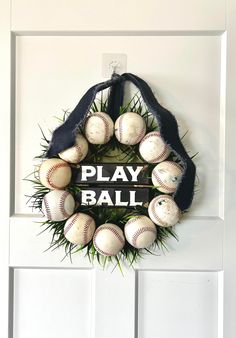 a wreath with baseballs is hanging on the front door and says, play ball