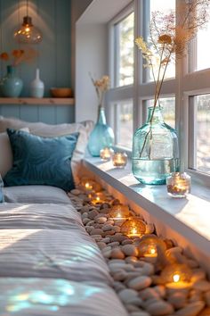 candles are lit on the windowsill in front of a bed with white sheets and pillows