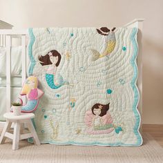 a child's bed with a mermaid quilt on it and a chair next to it