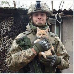 a soldier holding a cat in his arms