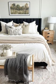 a bed with white sheets, pillows and blankets on top of it in a bedroom