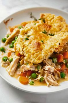 chicken pot pie with peas and carrots on a white plate, ready to be eaten