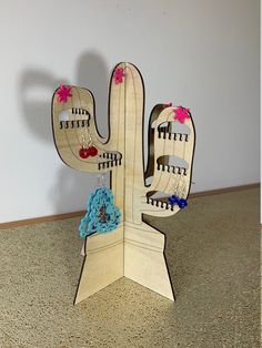 a wooden cactus with earrings hanging from it's sides on a counter top next to a wall