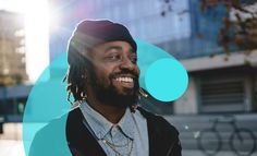 a man with dreadlocks smiles while standing in front of a blue and green circle