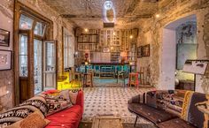 a living room filled with lots of furniture next to a wall covered in bookshelves