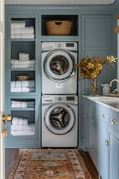 a washer and dryer in a blue laundry room with shelves full of towels