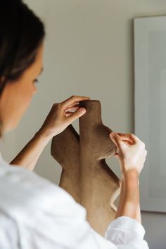 a woman is working on a sculpture in her home studio, with one hand holding the base