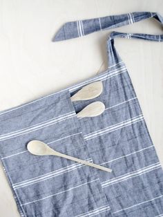 two wooden spoons are placed on top of a blue striped apron with white stripes